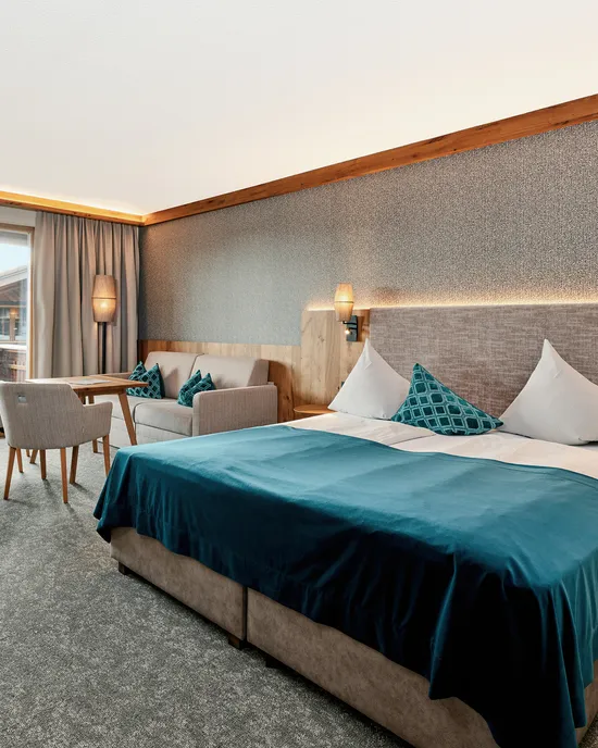 Moderna camera d'albergo con letto matrimoniale, area salotto e accesso al balcone